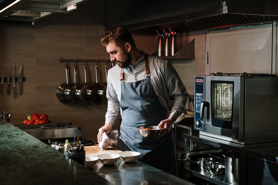 Male chef in a restaurant kitchen preparing a dish, showcasing culinary skills and expertise.