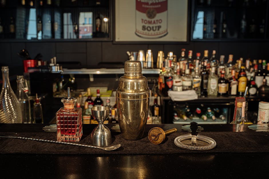 A well-equipped bar counter featuring cocktail shaker, liquors, and mixing tools in a cozy indoor setting.