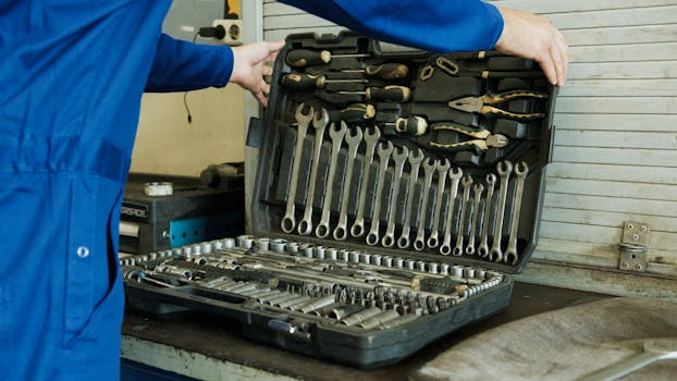 Mechanic organizing a comprehensive tool set for vehicle maintenance in a workshop setting.